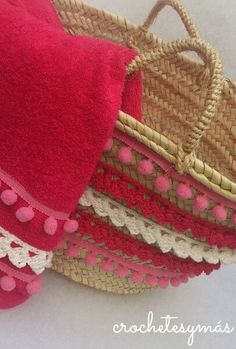 three baskets with pink and white pom poms on them, one is holding a straw bag