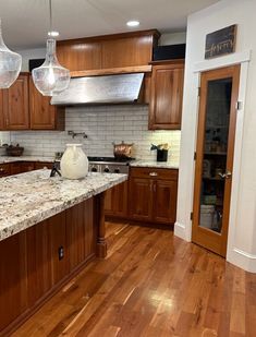 a kitchen with wooden cabinets and marble counter tops