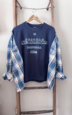 Seahawks Sweatshirt + Flannel Rework Seattle Seahawks Sizing: Sizing is very forgiving on these pieces. They are created to be a more oversized fit. Please see measurements and approximate sizing below. APPROXIMATE SIZE for this particular rework:  Will fit sizes SMALL - 3XLARGE  PLEASE be sure to measure yourself with the provided measurements below and keep in mind that these are supposed fit a bit more oversized. MEASUREMENTS: Shoulder to Shoulder - 20" Shoulder to Bottom Hem - 23" Armpit to Armpit - 35" Our reworks are carefully pieced together with lots of love! Each piece is completely one of a kind. We use a mix of new, pre-loved and thrifted items to create each piece. Flannel Sweatshirt Diy, Sweatshirt Upcycle Diy, Upcycle Shirts, Reworked Flannel, Reworked Sweatshirts, Recycled Shirts, Flannel Sweatshirt