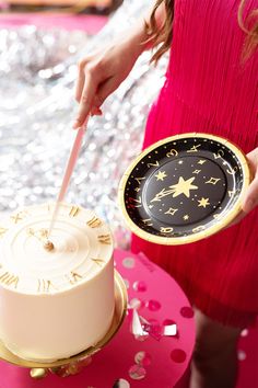 a woman holding a plate with a cake on it and a knife sticking out of it