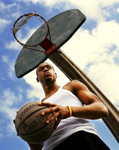 a man holding a basketball in his right hand and standing next to a basketball hoop