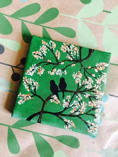 a small square painted with birds sitting on a tree branch