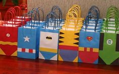 many bags are lined up on the floor in different colors and designs, all with batman symbols