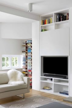 a living room filled with lots of white furniture and bookshelves next to a window