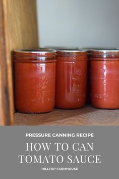 three jars filled with tomato sauce sitting on top of a wooden table