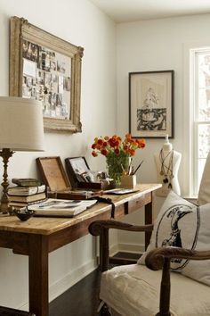 an image of a desk with flowers in the vase and pictures on the wall behind it