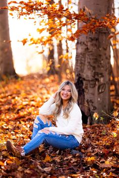 a woman sitting on the ground surrounded by leaves