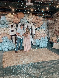 two people standing in front of balloons and letters that spell out the word bday