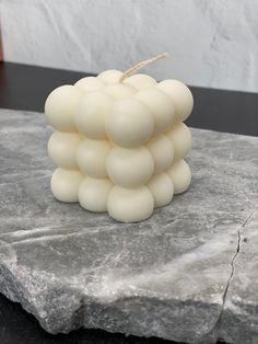 a white candle sitting on top of a stone slab