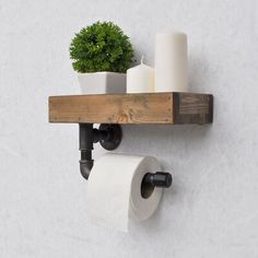 a wooden shelf with two rolls of toilet paper and a potted plant on it