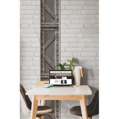 a laptop computer sitting on top of a wooden table in front of a white brick wall