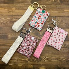 four key chains with different designs on them sitting next to each other in front of a wooden background