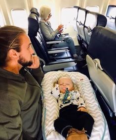 a man sitting next to a baby in an airplane