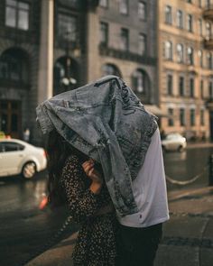 a man and woman walking down the street with an old jean jacket on their head