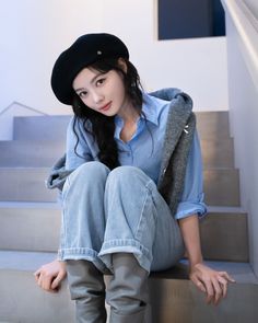 a woman is sitting on the stairs wearing jeans and a hat