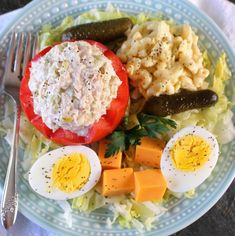 a plate with eggs, tomatoes, cucumbers and other food items on it