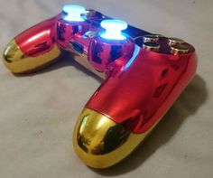 a close up of a shiny gold and red video game controller with two lights on each side