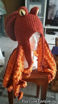 a crocheted octopus hat on top of a wooden table next to a white mannequin's head