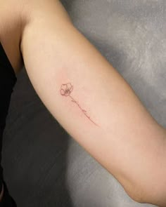 a woman's arm with a single flower tattoo on the left side of her arm