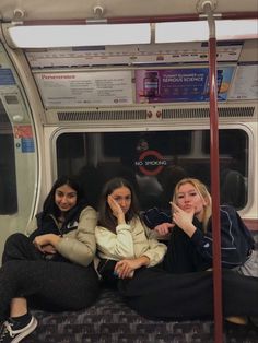 three women sitting on a subway train next to each other