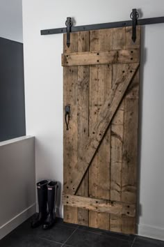 a pair of black boots sitting next to a wooden door