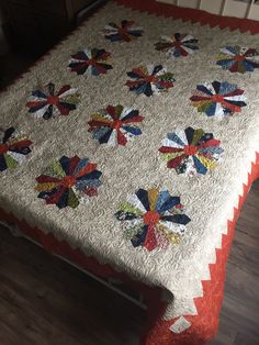 a quilted table cloth with red, white, and blue flowers on it sitting on top of a bed