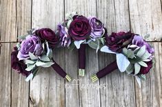 three bouquets of purple flowers are arranged in the shape of hearts on a wooden surface