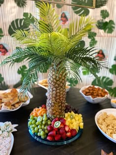 a table topped with plates and bowls filled with food next to a palm tree on top of a wooden table