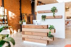 an office with plants on the wall and shelves above it, in front of a brick wall