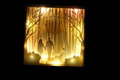 two people are walking through the woods with their dog at night, paper cut art