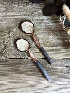 two wooden spoons sitting next to each other on top of a wooden table with dried flowers