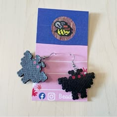 two earrings made out of plastic beads sitting on top of a piece of paper next to each other