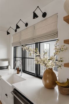 a vase with flowers in it sitting on a counter next to a sink and window