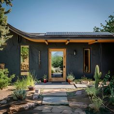 a house with a solar panel on the roof and side door, surrounded by cactuses