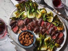 a plate with steak, lettuce and sauce on it next to glasses of wine