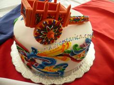 a birthday cake decorated with colorful decorations on top of a red and white table cloth