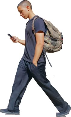 a man walking while looking at his cell phone and holding a backpack on his back