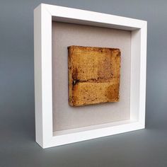 a piece of wood in a white frame on a gray surface with the bottom half missing