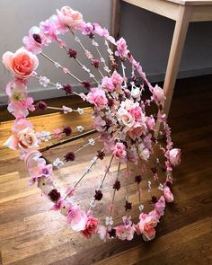 an umbrella made out of flowers sitting on top of a wooden floor