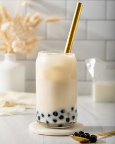 a glass filled with milk and blackberries on top of a table