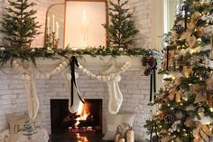 a decorated christmas tree in front of a fireplace with stockings hanging from the mantel