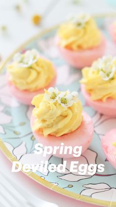 small pink and yellow cupcakes with white flowers on them sitting on a plate