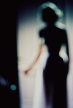 a blurry photo of a woman standing in front of a window with her shadow on the wall