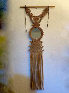 a wall hanging with a mirror and tassels attached to it's side