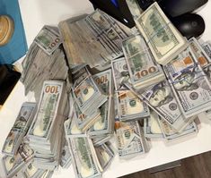 a pile of money sitting on top of a desk next to a computer keyboard and mouse