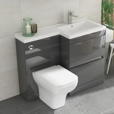 a white toilet sitting next to a sink in a bathroom under a window with green plants