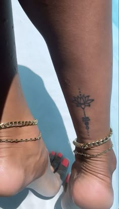 a woman's foot with a cross tattoo on her left ankle and chain around the ankles