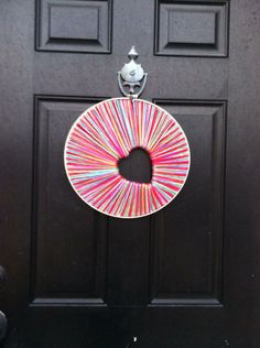 a black door with a pink and yellow wreath hanging on it