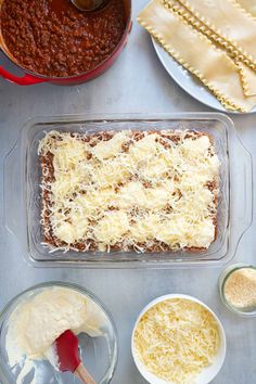 ingredients for baked lasagna laid out on a counter top, including cheese and sauce