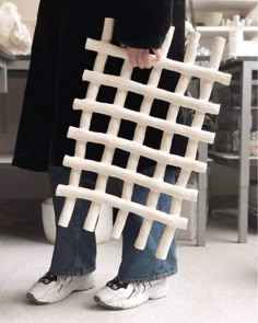 a person standing in front of a chair made out of white plastic pipes and sticks